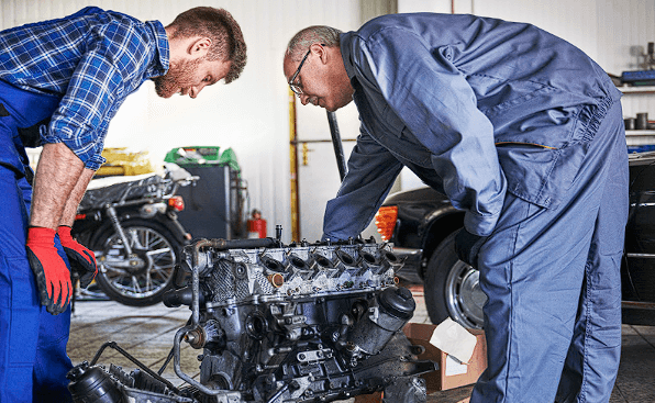 Mechanics disassembling a car engine, carefully preparing for shipping car parts